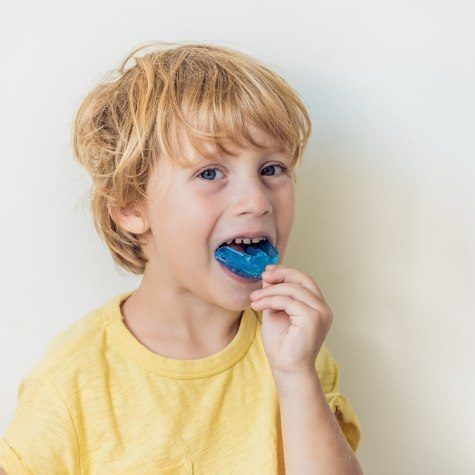 Young child placing athletic mouthguard