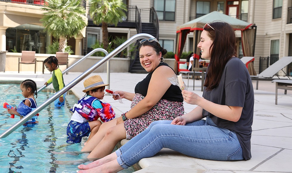 Two dental team members laughing with feet in the pool