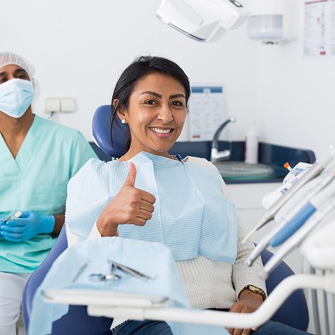 a dental patient smiling and giving a thumbs up