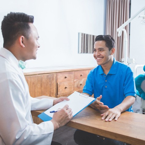 man smiling while talking to dentist  