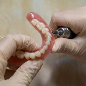 Lab technician filing dentures