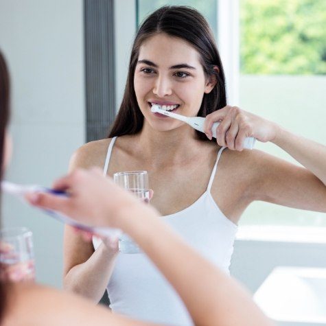 Woman brushing teeth to prevent dental emergencies