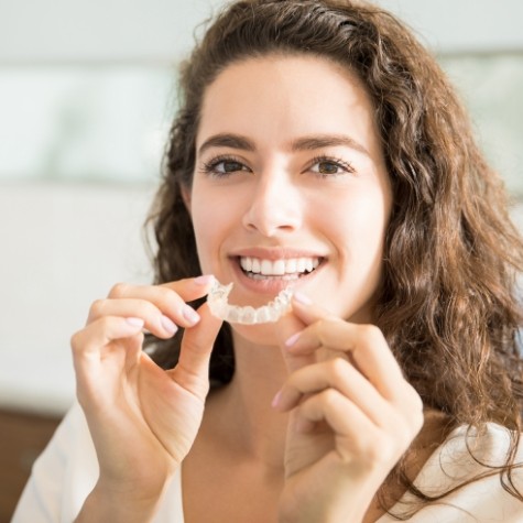 Smiling woman placing an Invisalign clear braces tray