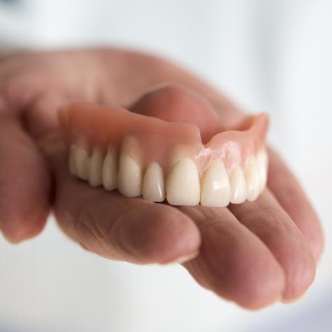 Hand holding full denture