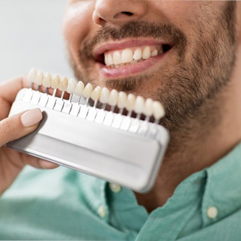 Dentist holding row of veneers next to dental patient