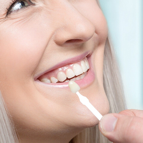 woman smiling at dentist as he holds up color tester