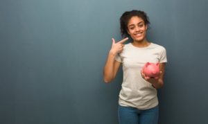 patient smiling and holding a piggy bank